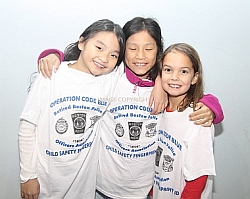A photo of three young girls with arms around each other wearing white Operation Code Blue t-shirts